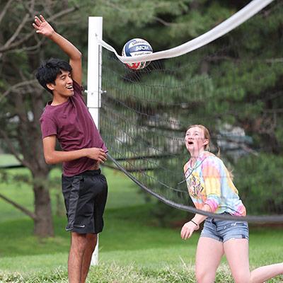Students playing sand volleyball at party in the park